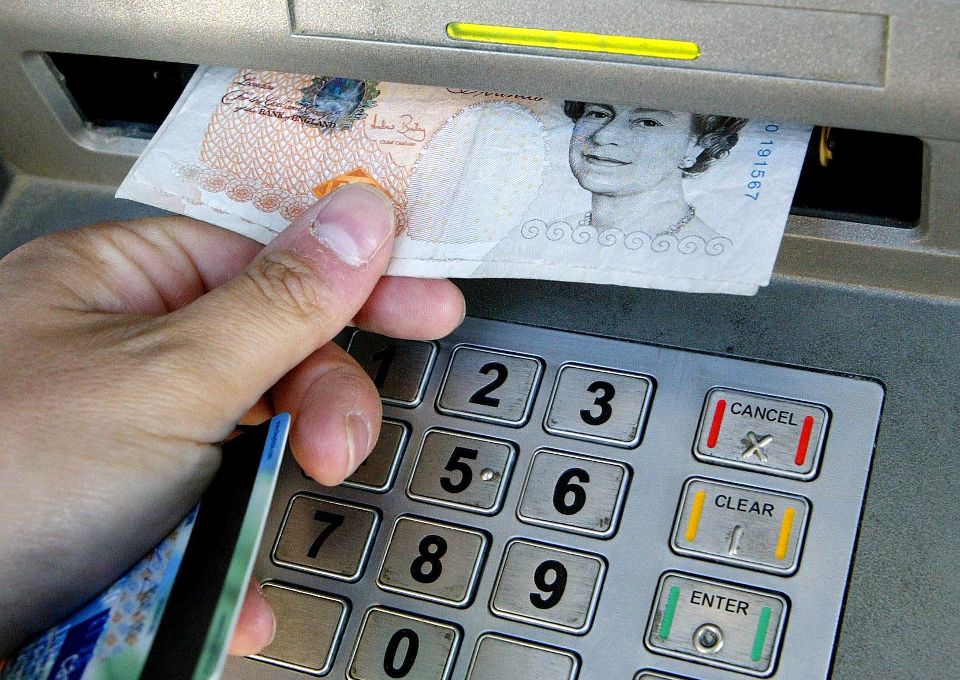 A hand taking a £10 note from a cash machine