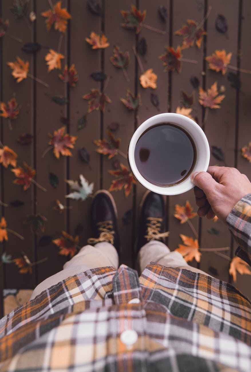 a person wearing a plaid shirt holding a cup of coffee