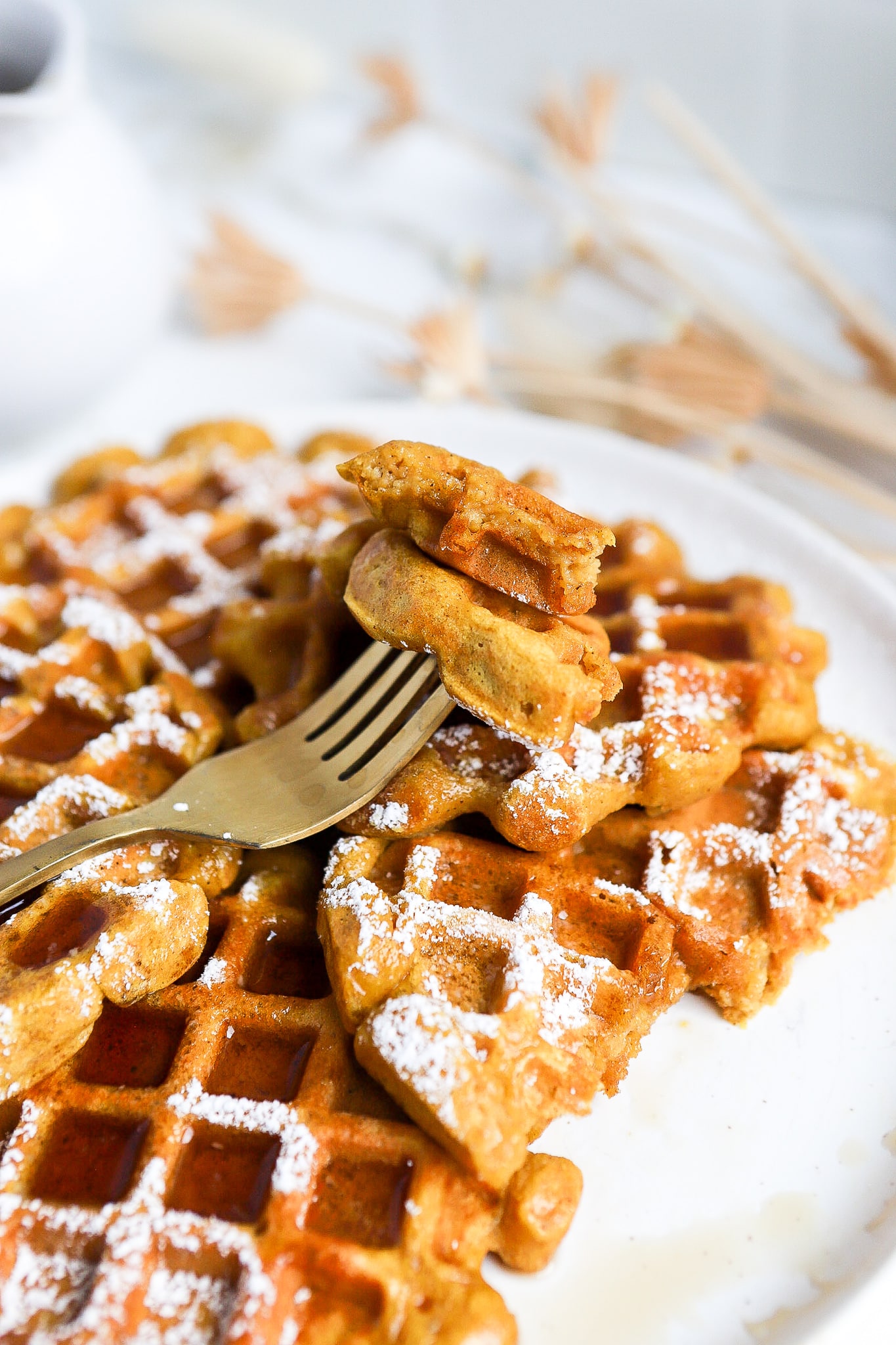 Bite of an easy pumpkin waffle on a gold fork showing the fluffy inside