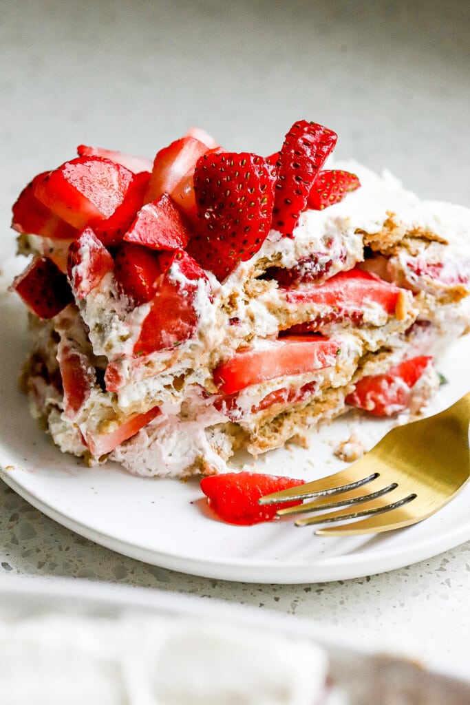 Slice of no bake strawberry icebox cake on a plate showing soft graham cracker layers