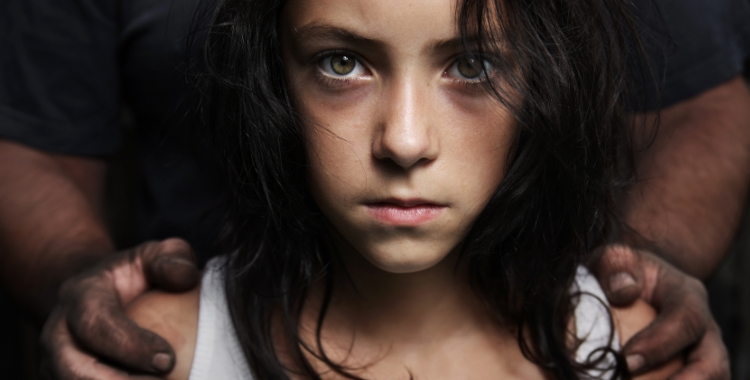 Child with an adult’s hands resting on her shoulders