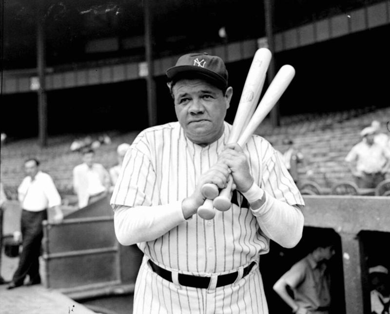 A picture of Babe Ruth in a Yankees uniform holding three baseball bats.