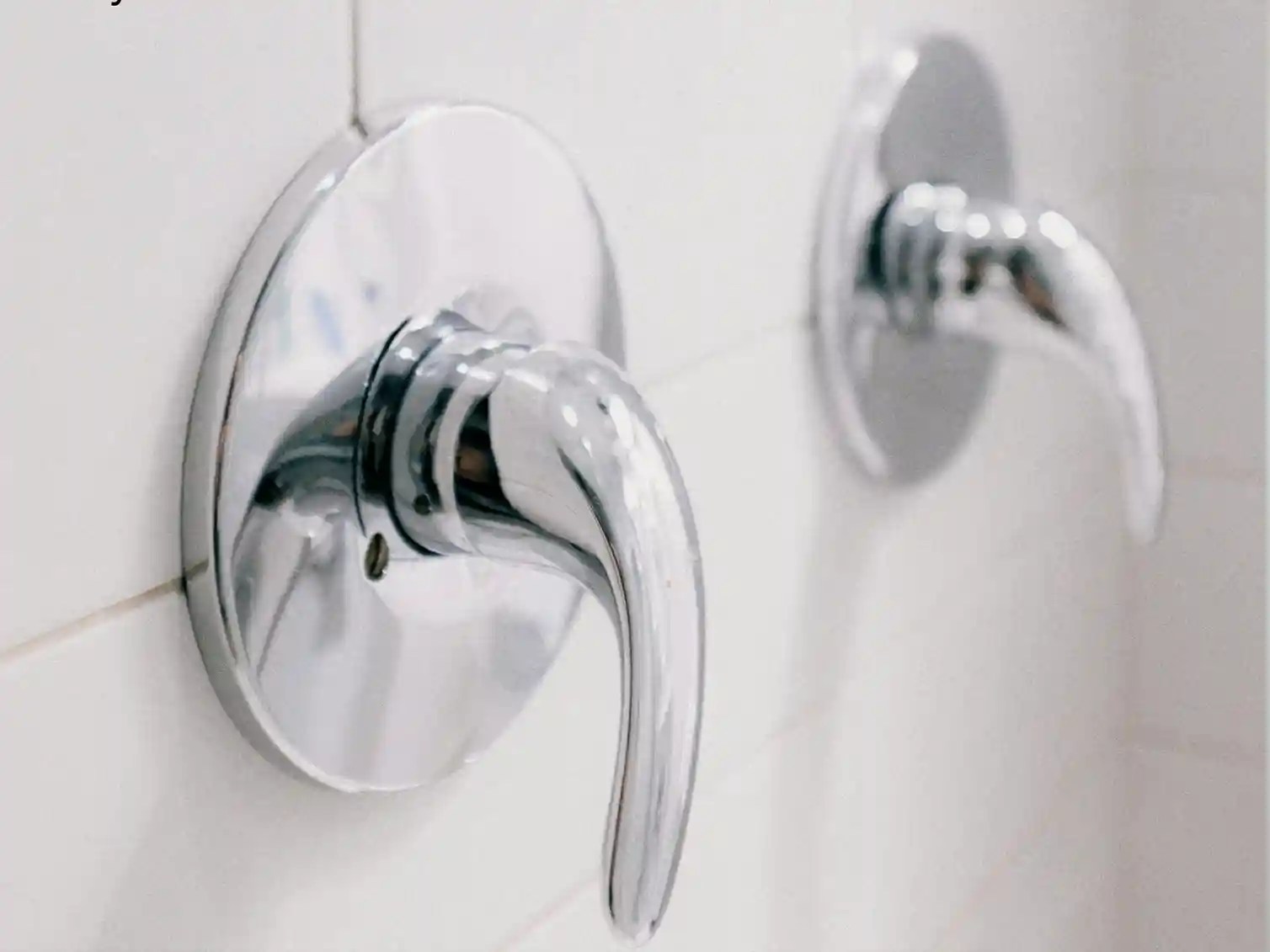 Stylish chrome shower fixtures, including a modern showerhead and shelving, in a tub-to-shower conversion.