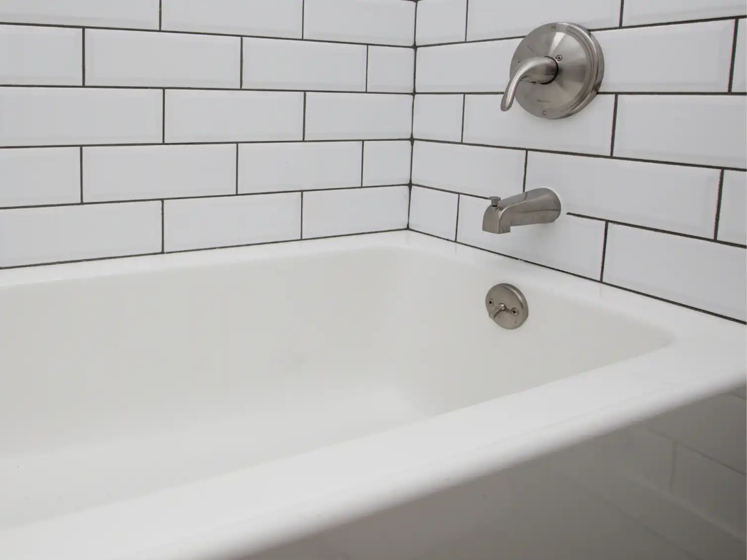 Classic white acrylic bathtub surrounded by durable subway tile, showcasing timeless and easy-to-clean materials