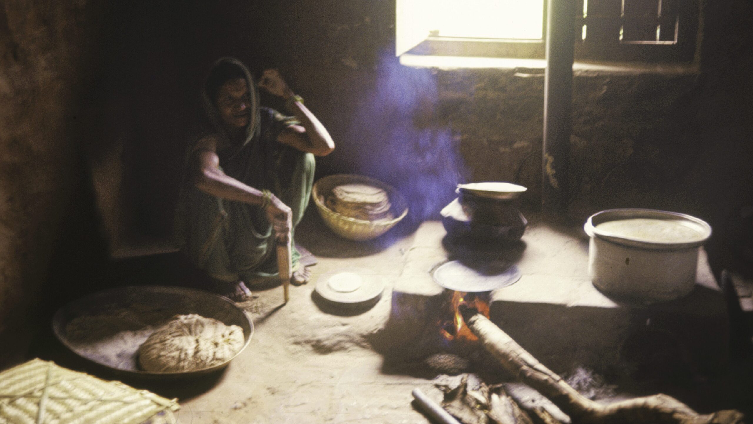Indian woman making chapati (Indian bread) over an open fire