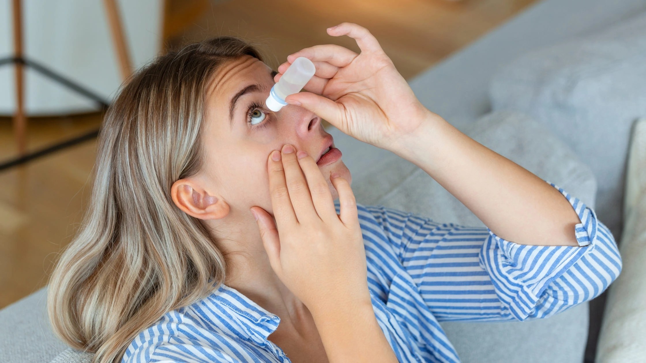 a girl putting eye drop in her eye