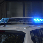Blue police lights activated on top of white police car.