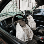Severely damaged car interior with deployed airbags and shattered windshield showing typical timeline from Alabama crash to settlement.