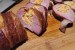 Bacon wrapped stuffed pork tenderloin sliced on a wood cutting board.