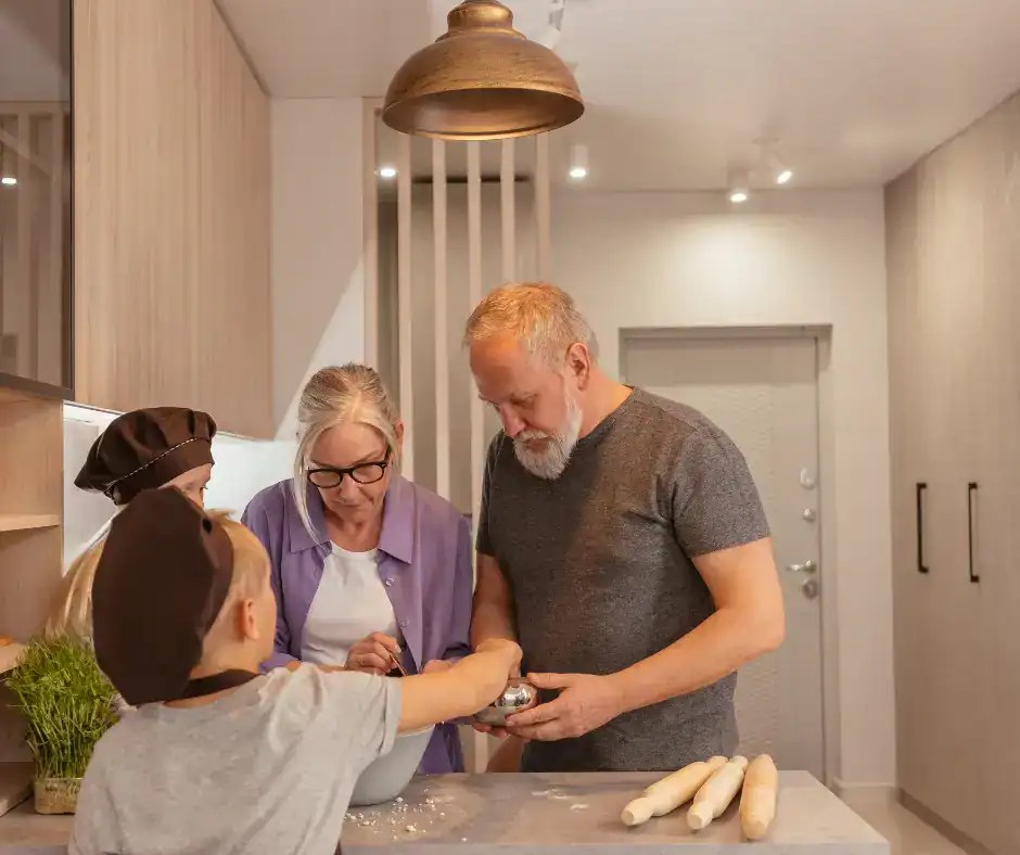 granparents and granchildren cooking in a kitchen with tall cabinets