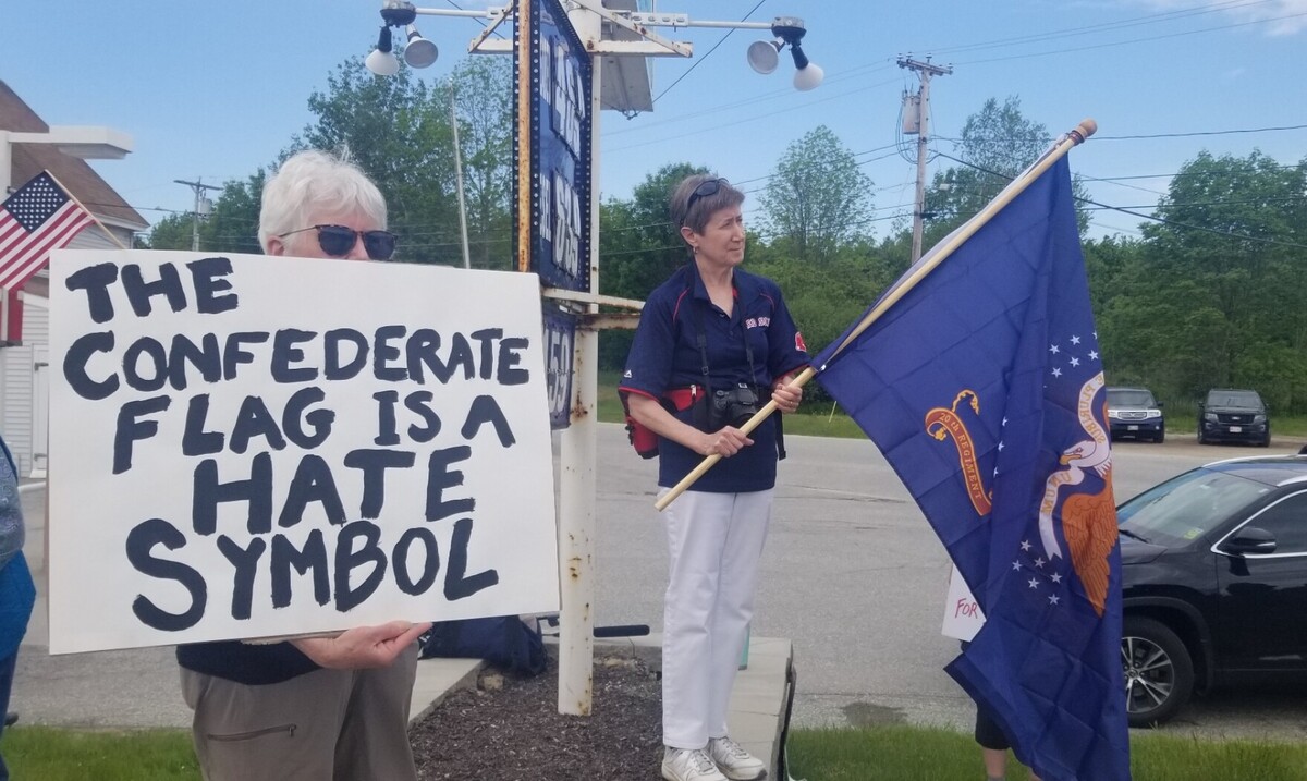 Women hold a white sign and blue flag.