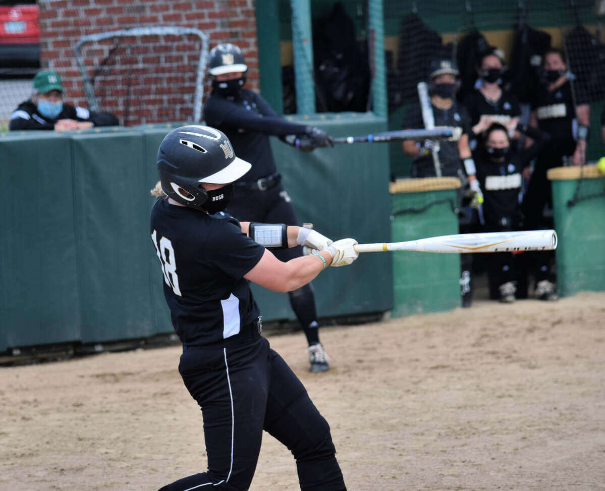 A softball player takes a swing of her bat