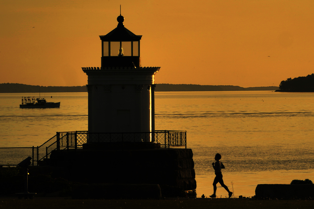 A jogger runs past a lighthouse in South Portland.
