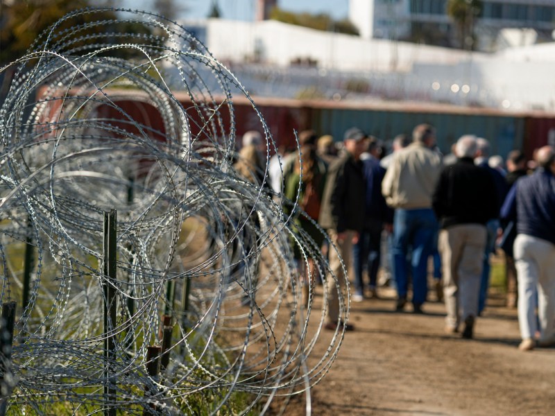 Concertina wire lines the path as members of Congress tour an area near the Texas-Mexico border in Eagle Pass, Texas.
