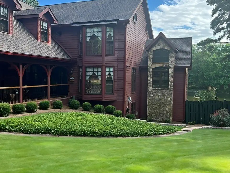 Home exterior with stone tower addition matching dark red siding and rooflines