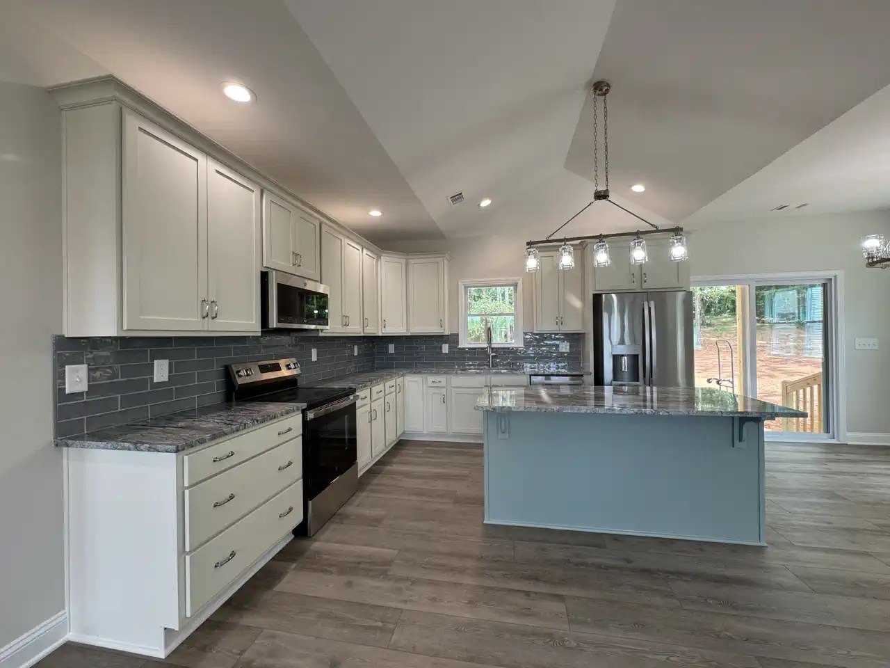 Open kitchen with white cabinetry, dark countertops, and blue-gray island