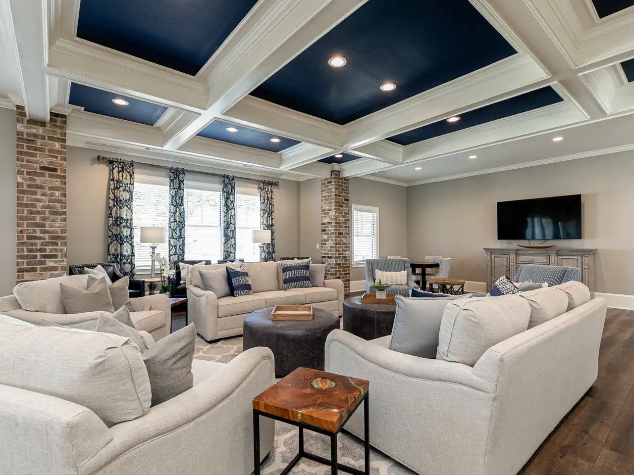 Clubhouse living room with coffered navy ceiling and brick support columns