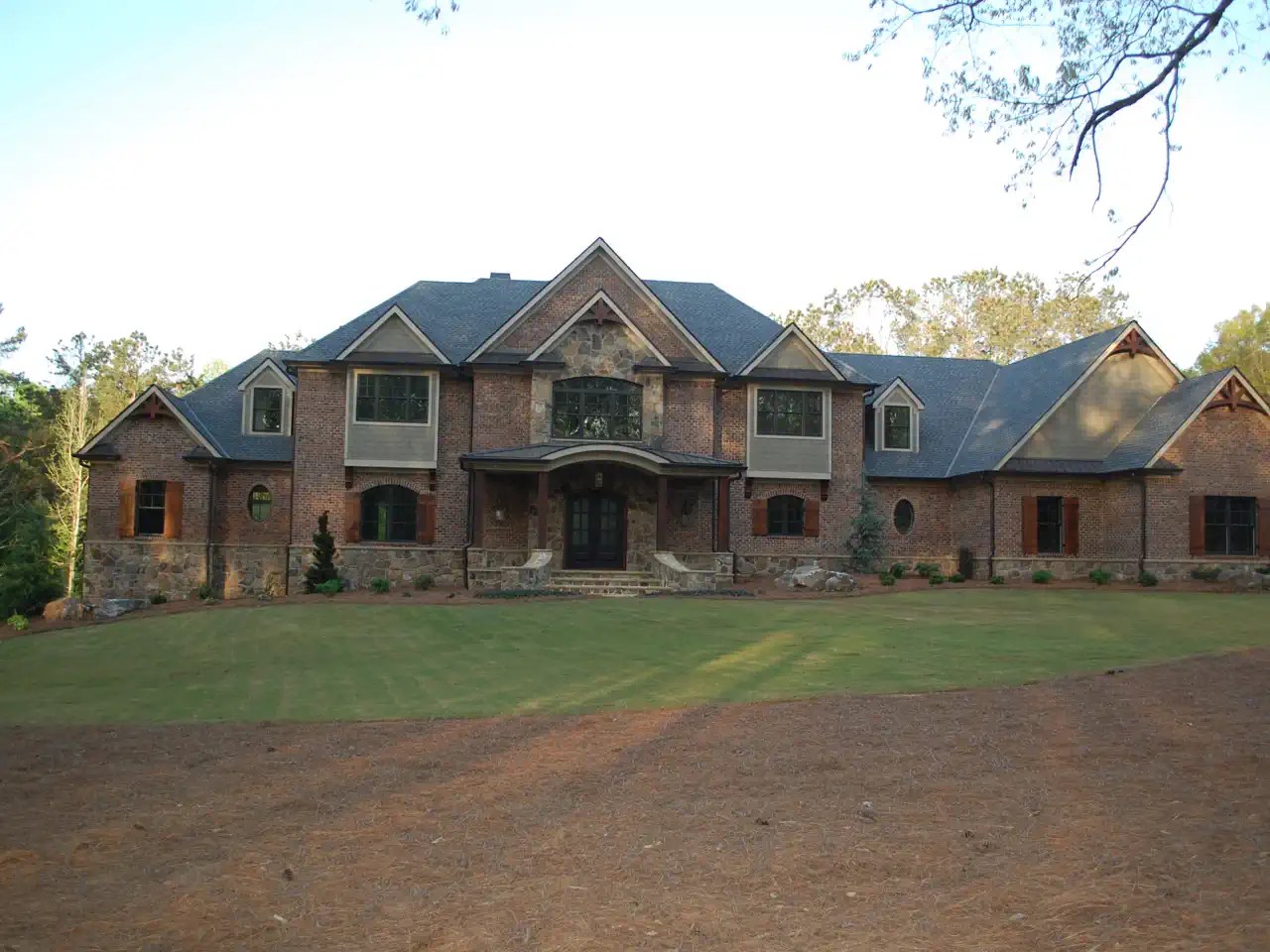 Large brick and stone estate with arched entry and dormer windows