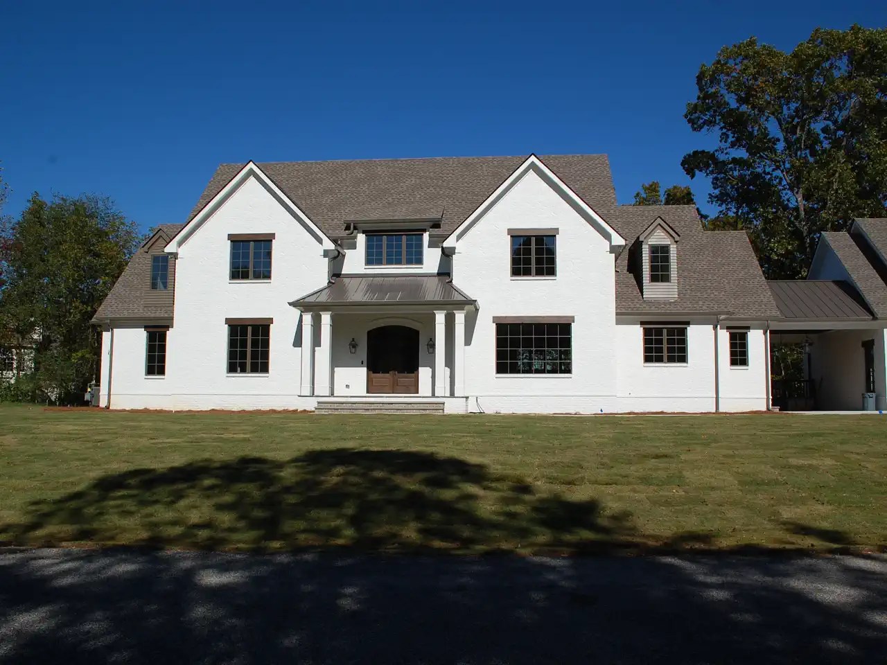 White painted brick home with columned portico connecting to an attached garage