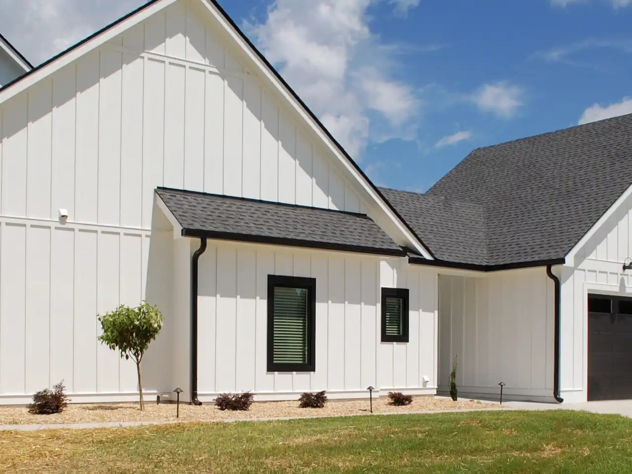 Side exterior view of a home with a tall attached garage and custom garage doors
