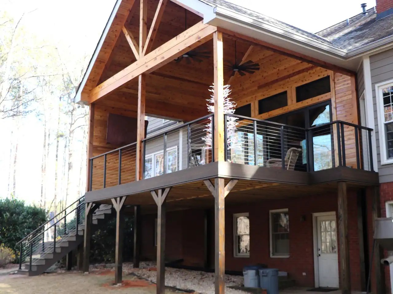 Raised covered deck with vaulted wood ceiling, cross beams, and cable railing