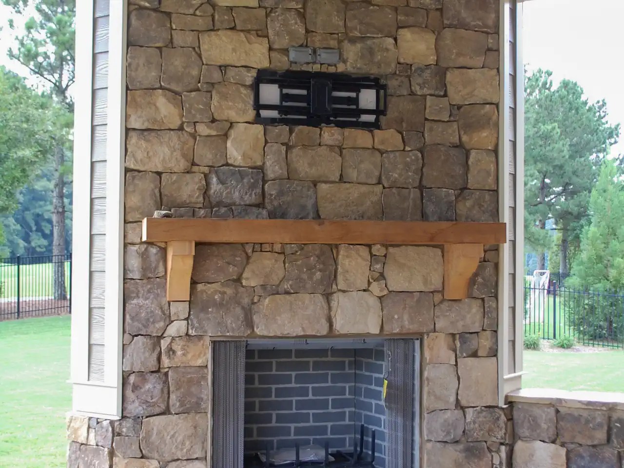 Stone fireplace with wood mantle, TV mount, and wood plank ceiling