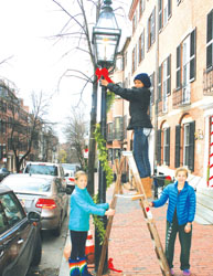 Decorating a lampost on Sunday afternoon on Chestnut St. were Tamira Kitchens on the ladder, Anne (left) and Camille Stockwell.