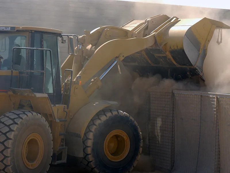 A wheel loader dumps biomass into a bin.