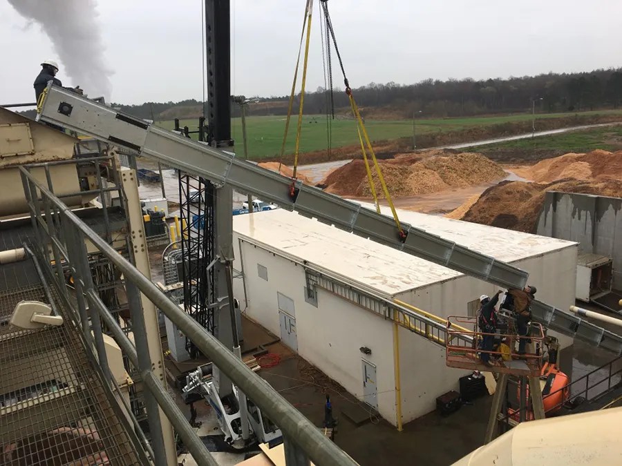 A crane holds a SMART Conveyor™ span in a construction site.