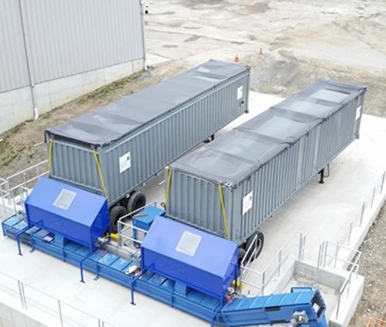 Walking floor containers backed up to receiving bins