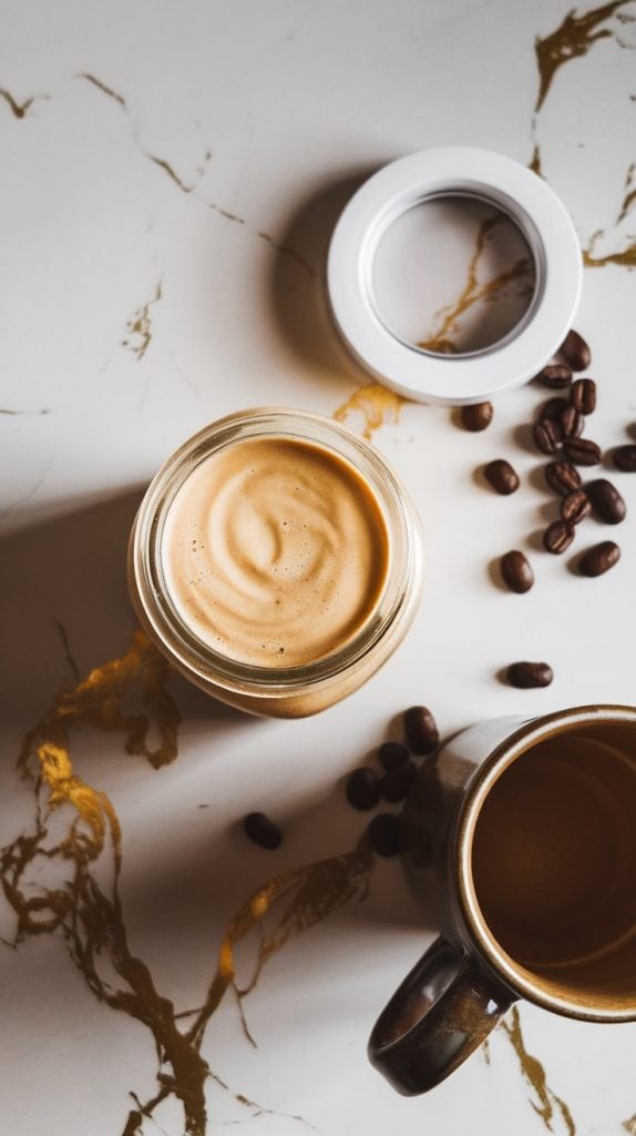 A glass jar filled with creamy butterscotch coffee creamer, with a lid nearby
