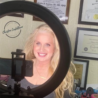 Christine smiling in front of a selfie ring light