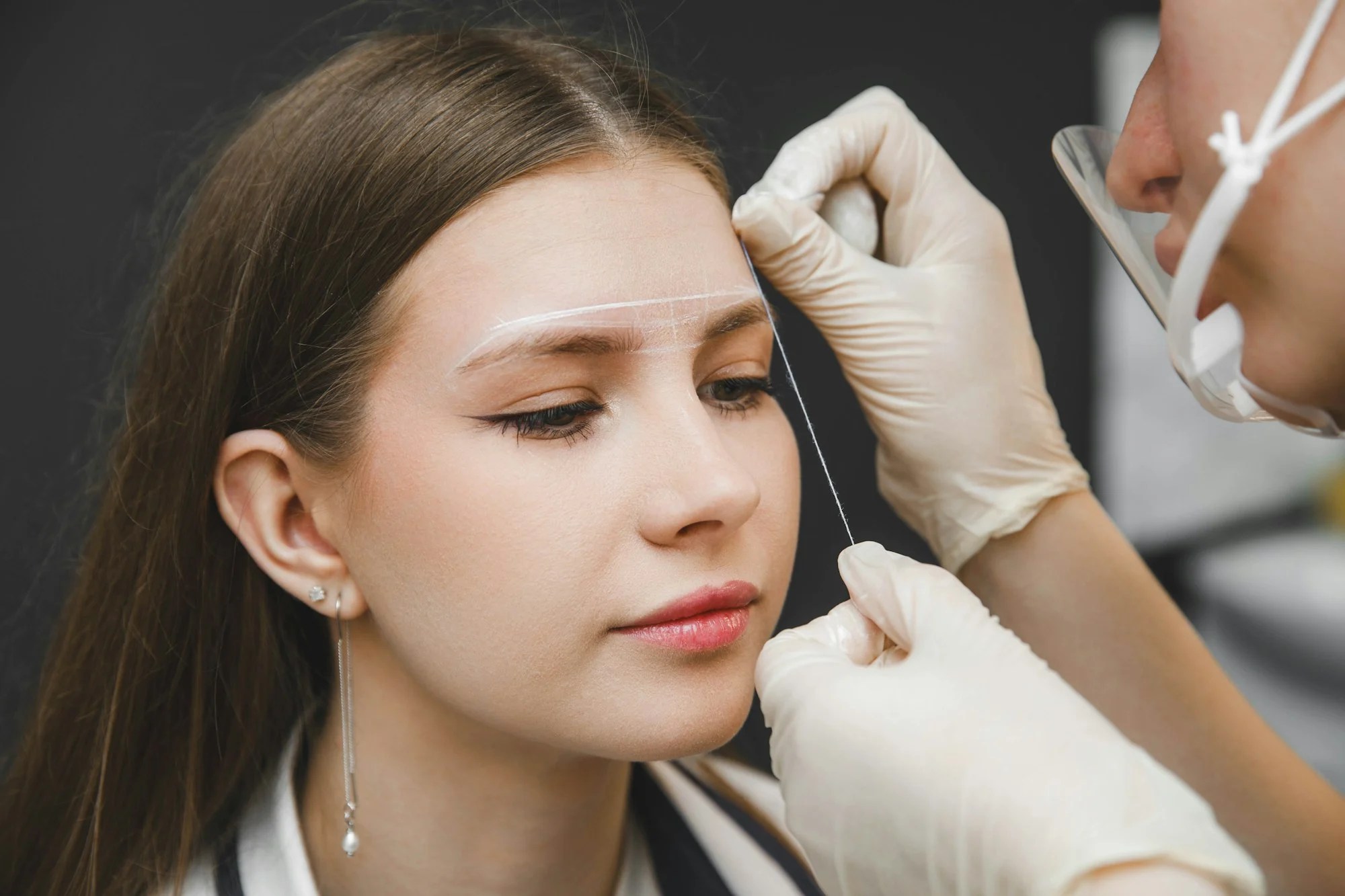 The master marks the eyebrows with thread. Permanent makeup. Permanent eyebrow tattoo.