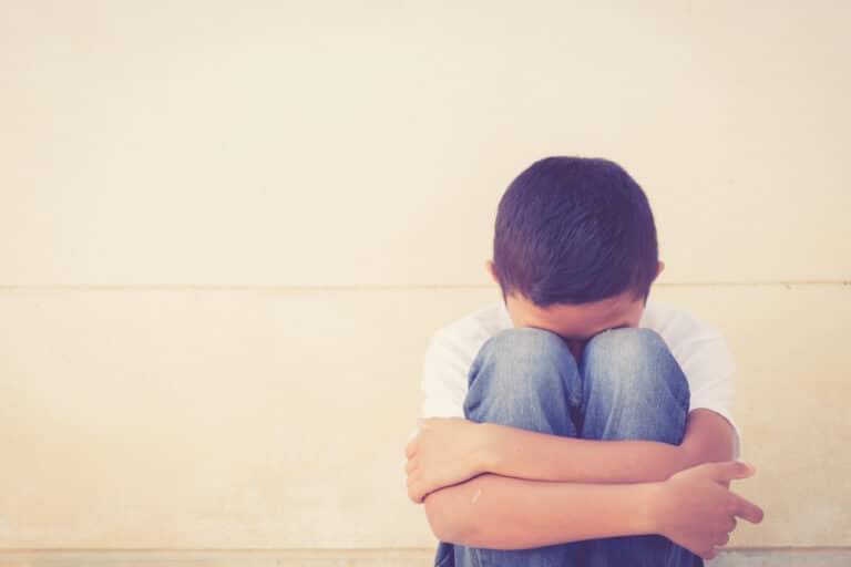 Sad child, head in knees