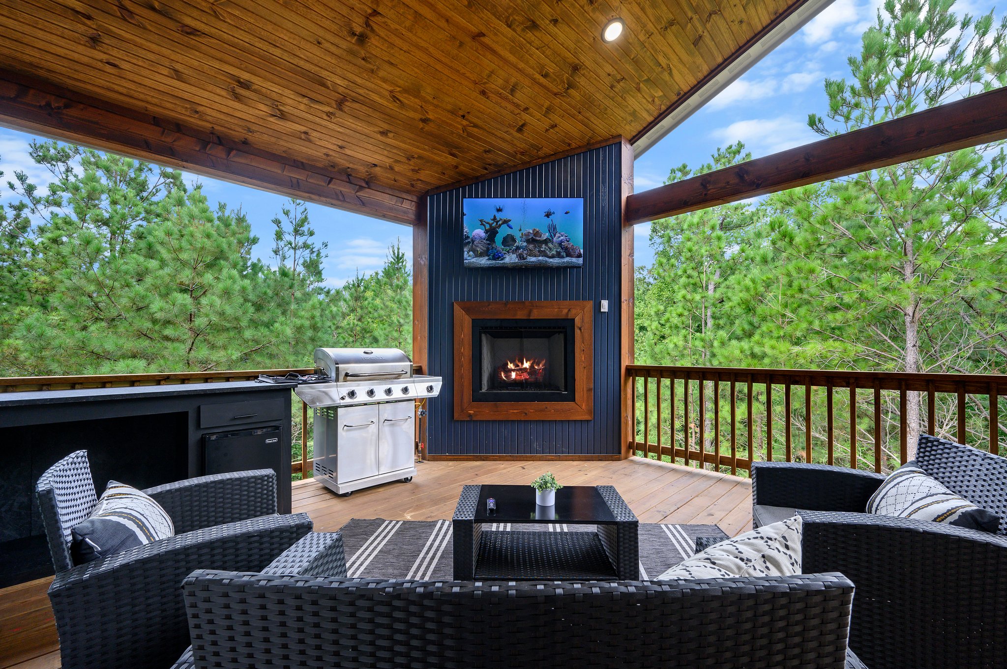 Outdoor seating gathered around the covered deck fireplace and television