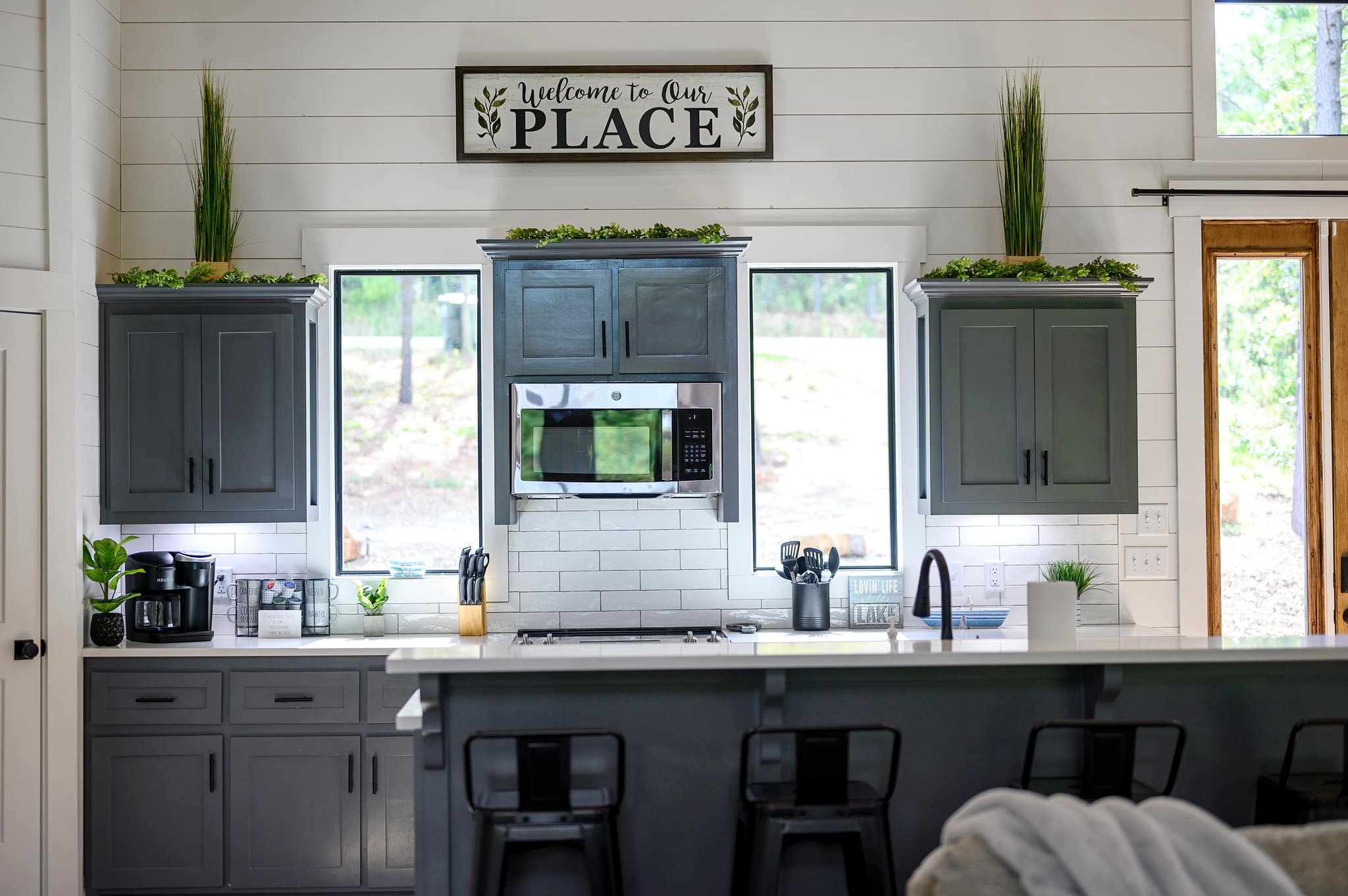 Kitchen with breakfast bar, gray cabinets, stainless steel appliances, and forest views