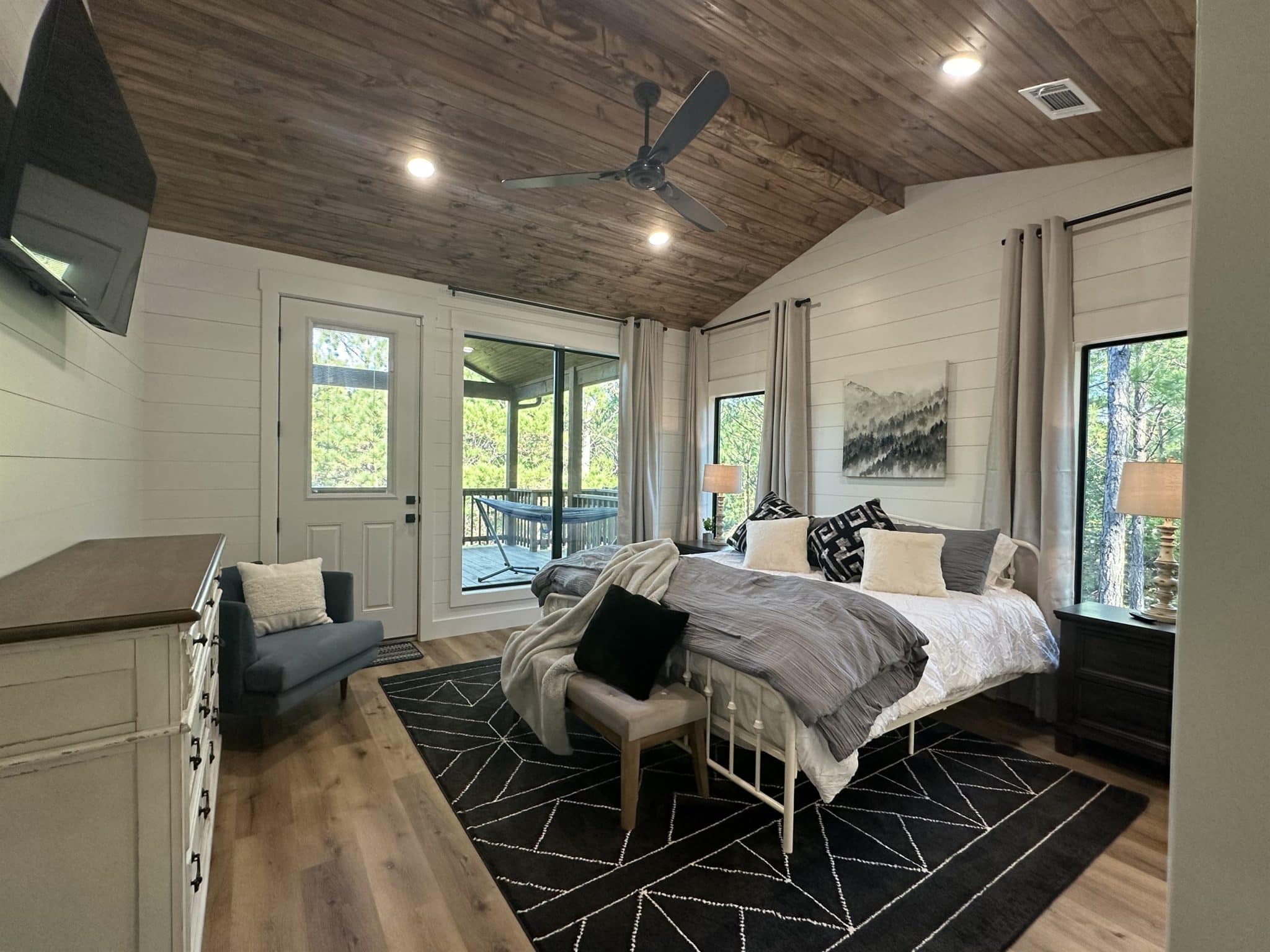 King bedroom with gray bedding, forest views, and private en-suite bathroom