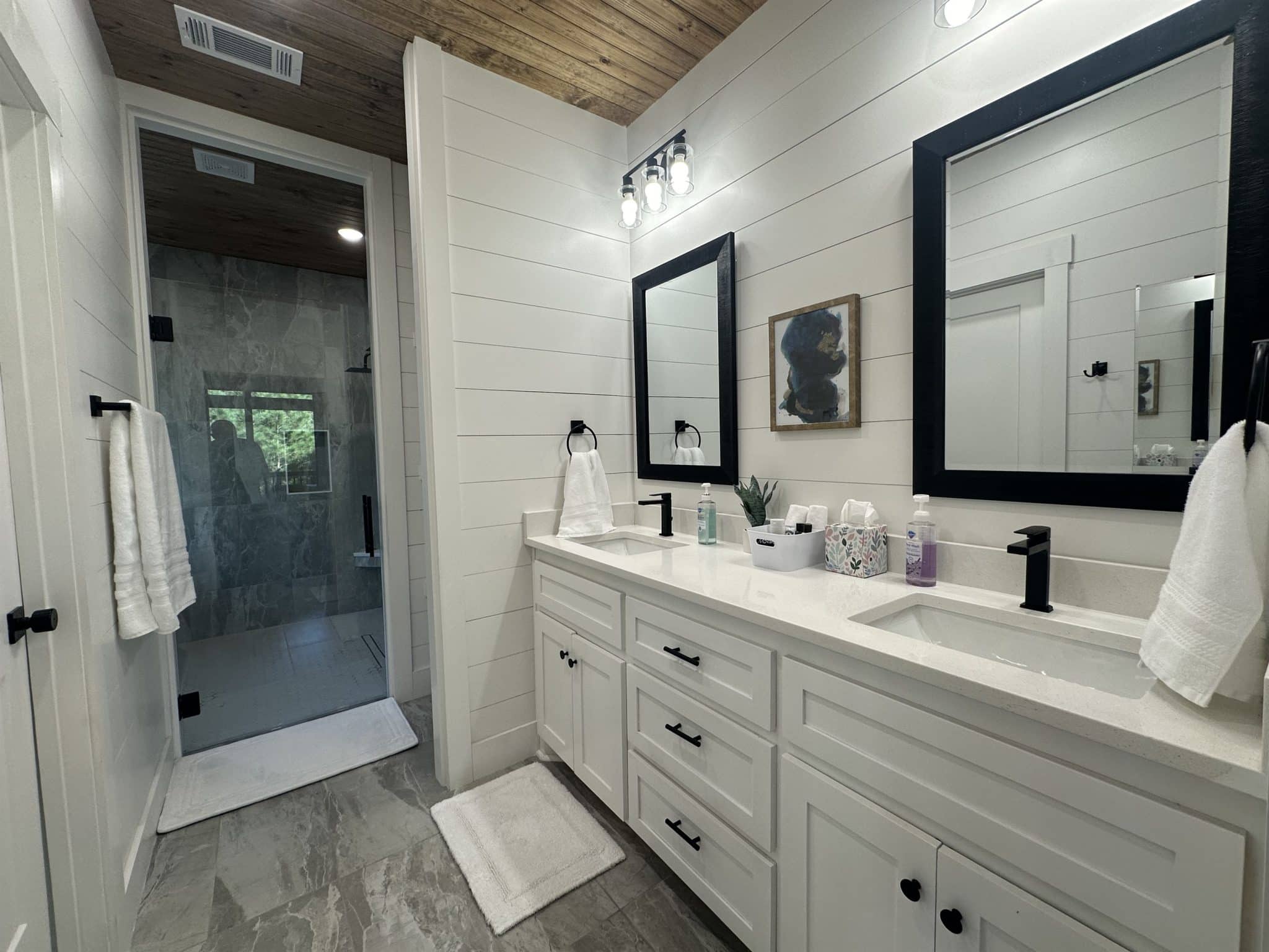 En-suite bathroom with white double vanity, black fixtures, and glass shower