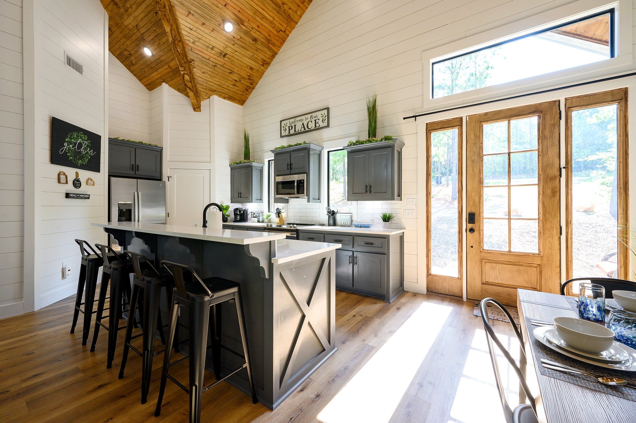 Kitchen island and dining area with vaulted wood ceiling and bright natural light
