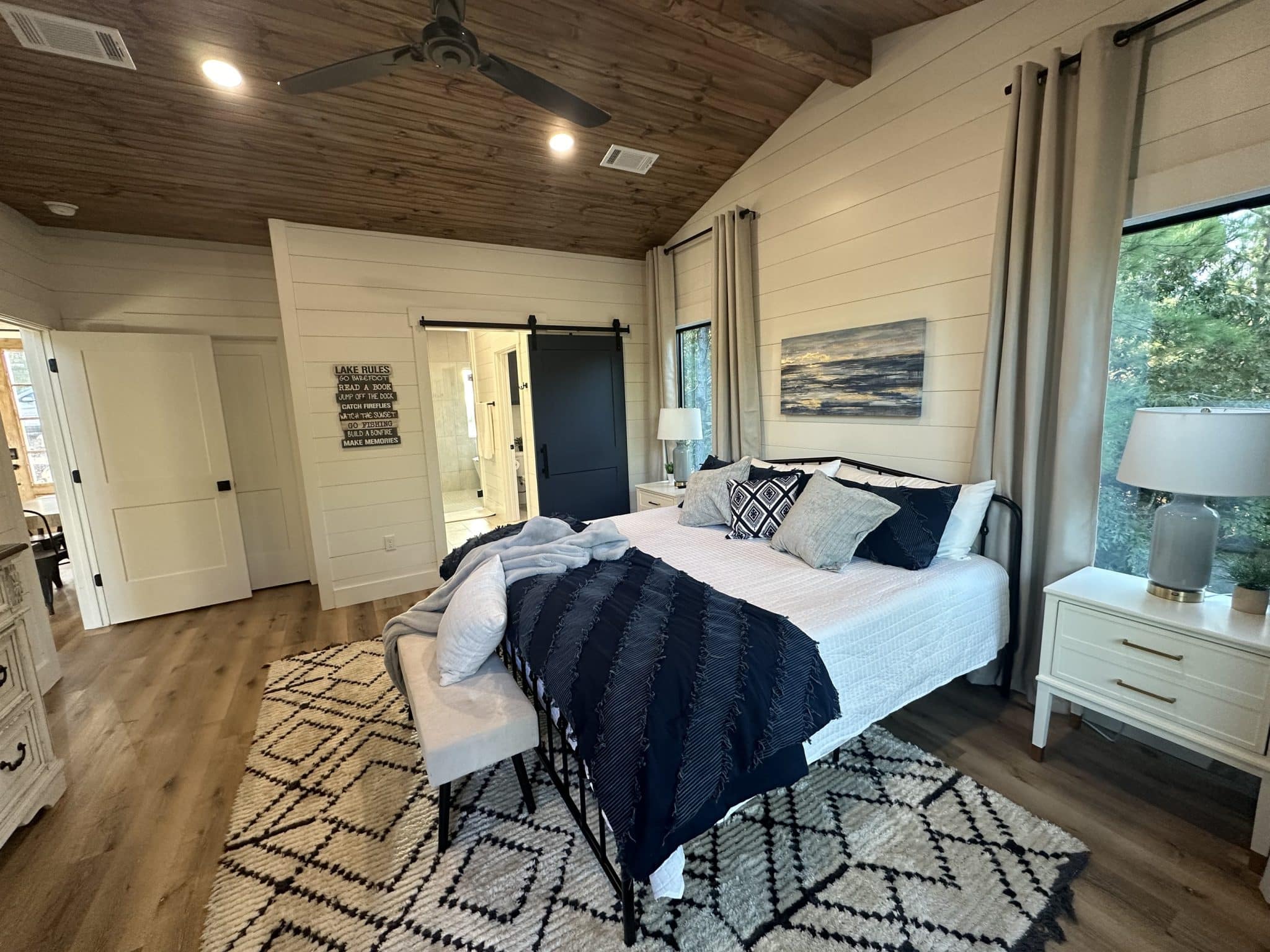 King bedroom with vaulted wood ceiling, forest-view windows, and en-suite bathroom