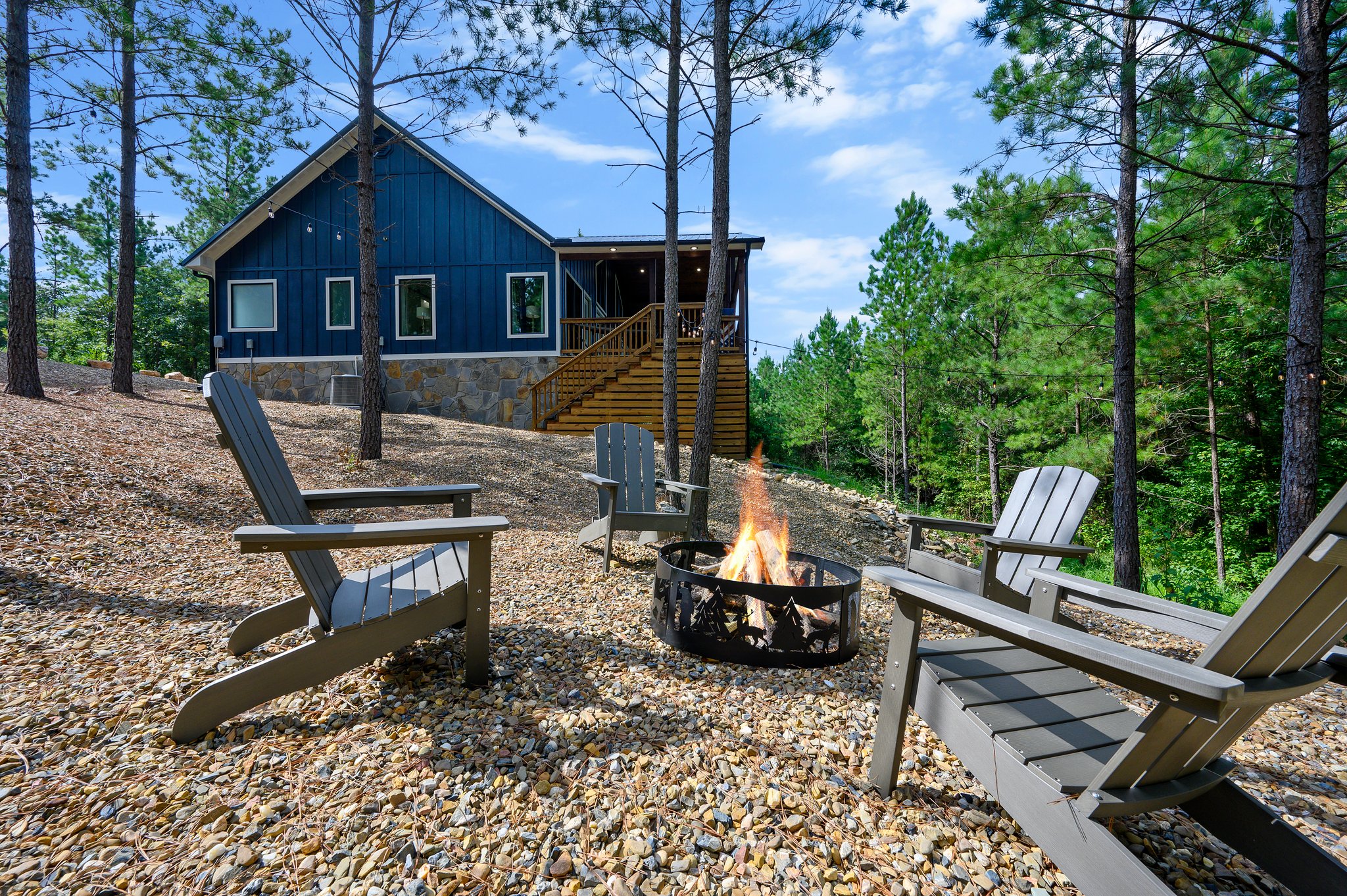 Fire pit with Adirondack chairs beside the cabin in the pine forest