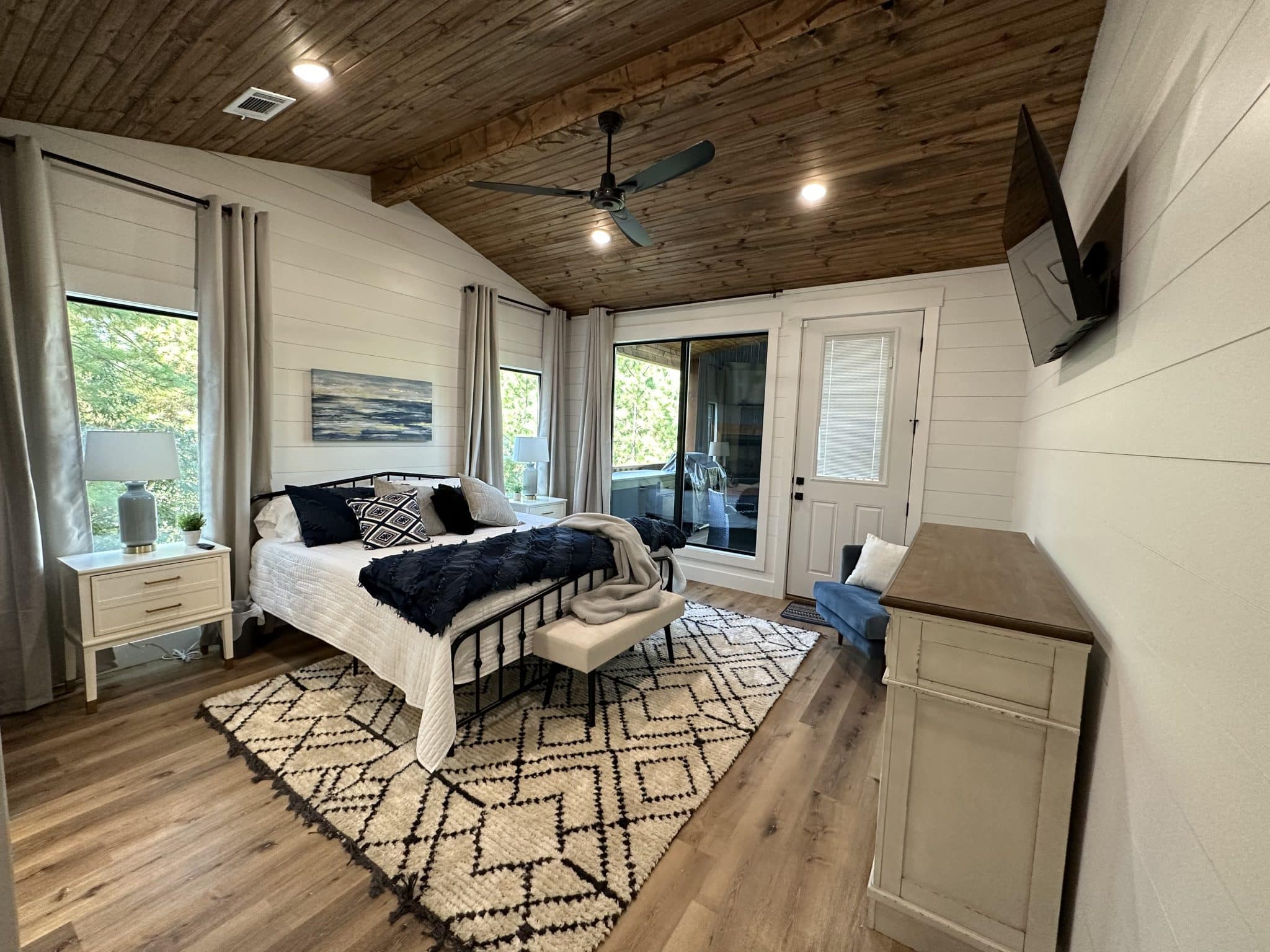 King bedroom with a vaulted wood ceiling and forest views at Beds, Boating & Beyond