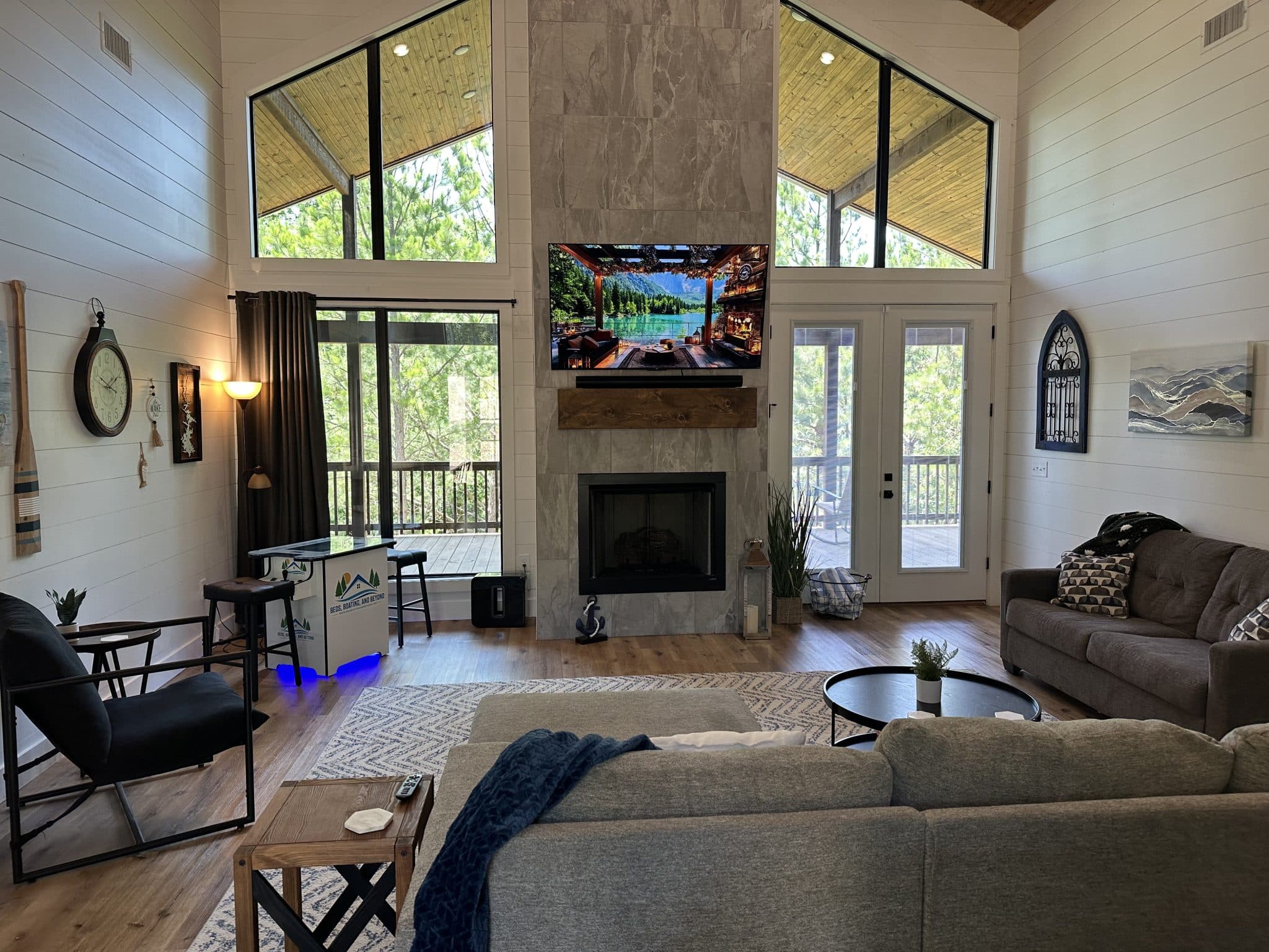 Open living room with a 24-foot fireplace and forest-view window wall at Beds, Boating, & Beyond in Hochatown