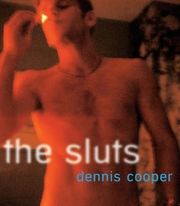 The cover of Dennis Cooper's The Sluts. An attractive nude man in his twenties lights a cigarette, his bare chest visible. The image is tinted orange and has a grainy quality. The title and author name are written in the style of a neon sign,