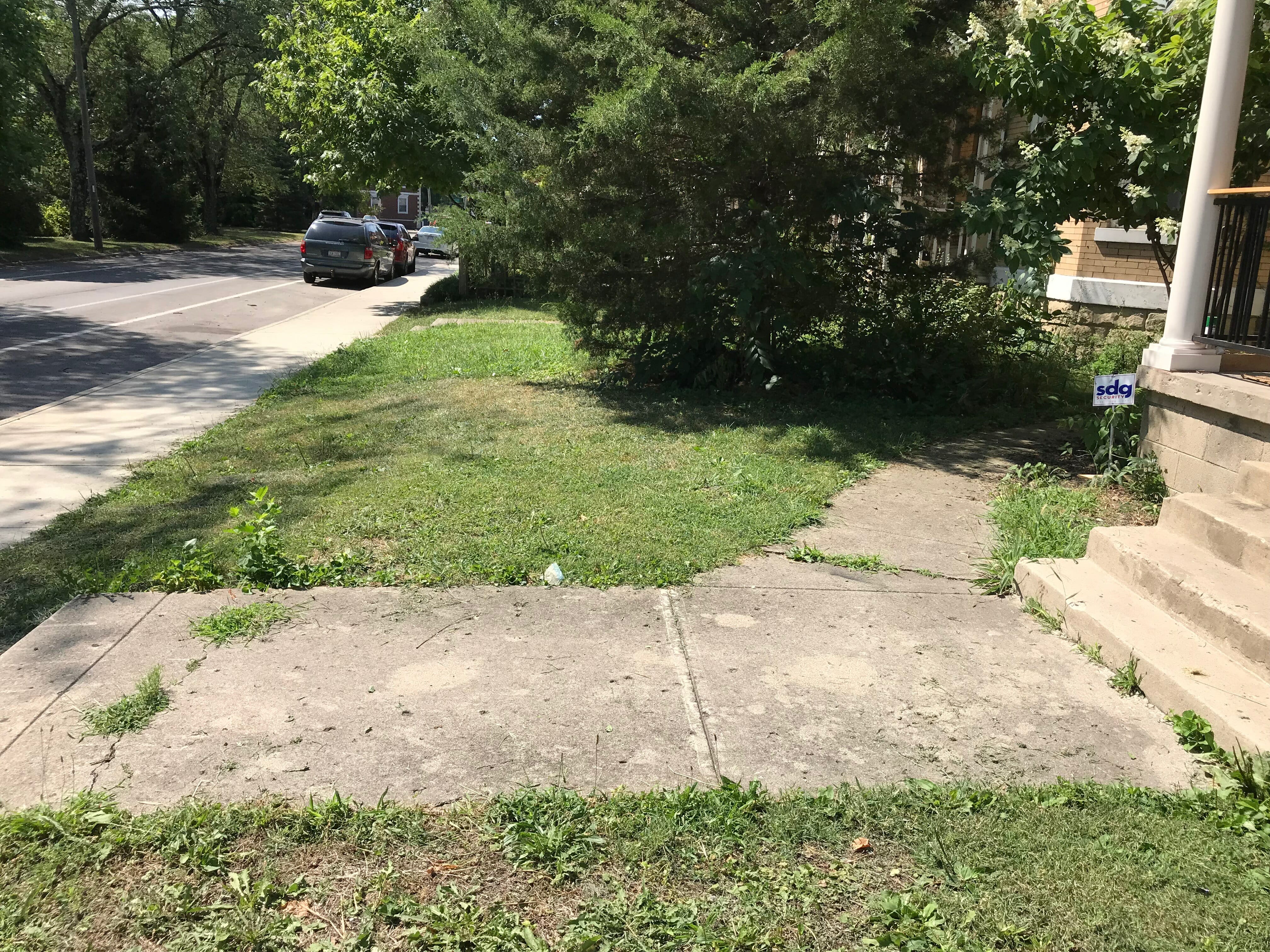 Someone using a measuring tape to mark out a walkway on the ground. Diy How To Install Pavers Over Old Concrete Beginning In The Middle