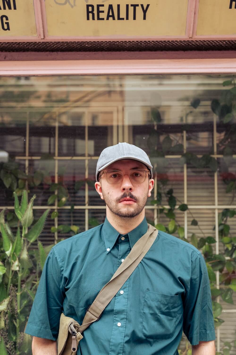 french man in sunglasses soft portrait in Prague, text "reality" at the background and plants