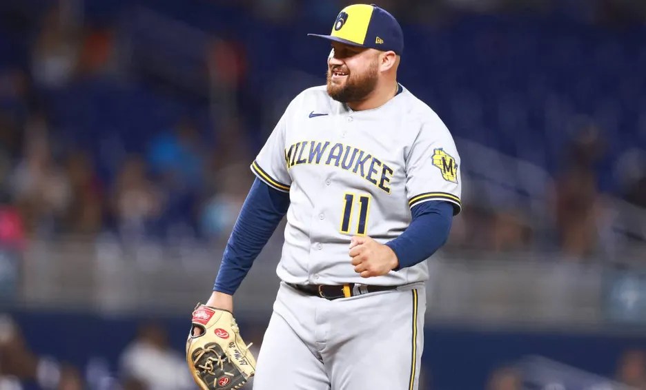 Pelotero de los Brewers con dorsal 11 en uniforme blanco y azul, sonriendo durante el juego con guante en mano