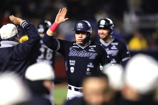 Pelotero de los Sultanes con uniforme negro levanta el brazo en celebración durante un juego nocturno