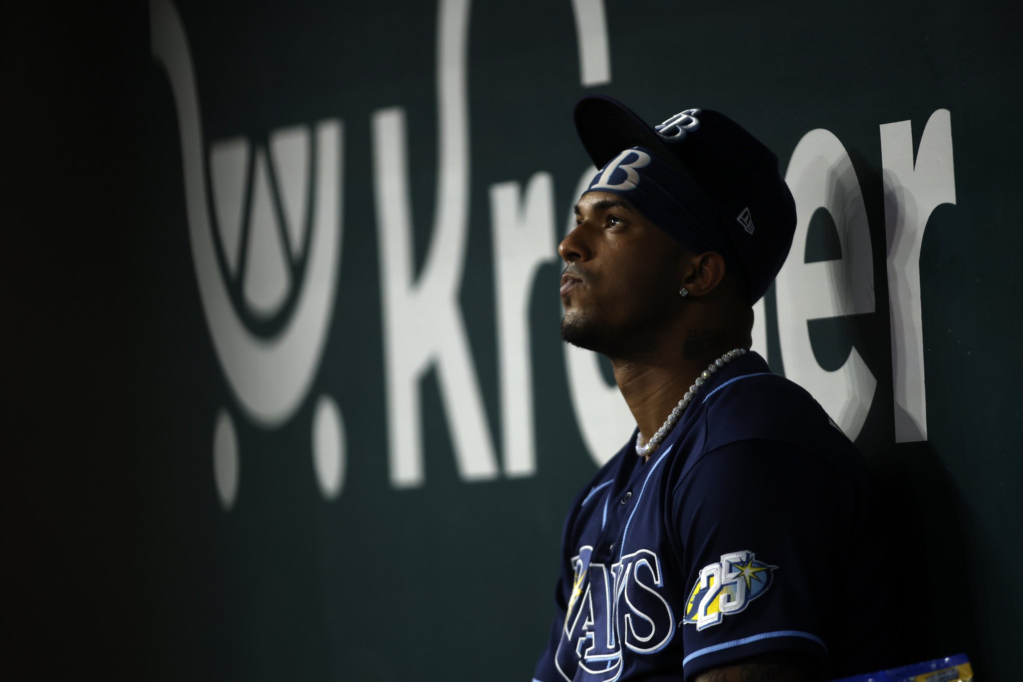 Pelotero con uniforme azul marino de los Rays en el dugout, mirando hacia el campo durante un partido