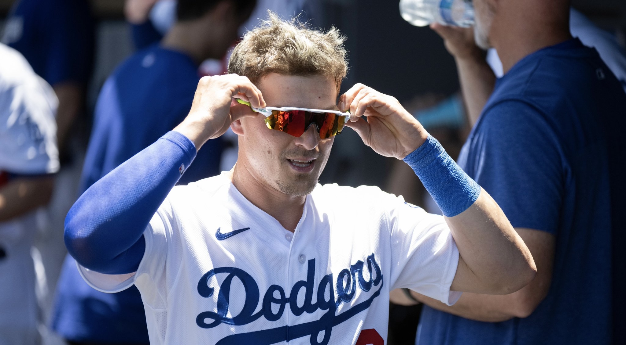Pelotero de los Dodgers en el dugout ajustándose las gafas de sol, uniforme blanco con logo del equipo
